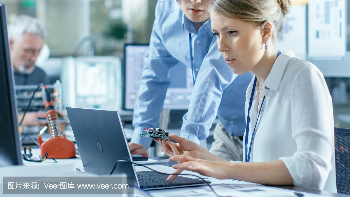 女計算機科學家將電路板連接到她的筆記本電腦并開始編程。她在先進技術實驗室工作。